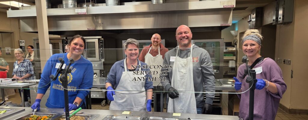 Volunteers serving food at a kitchen.